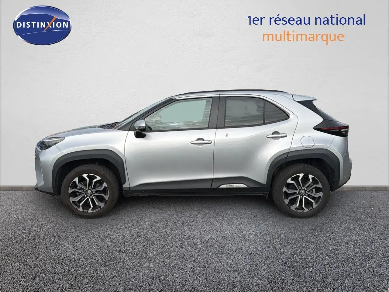 Profil côté gauche de la Toyota Yaris Cross gris minéral avec jantes bi-ton et protections noires sur les passages de roue.