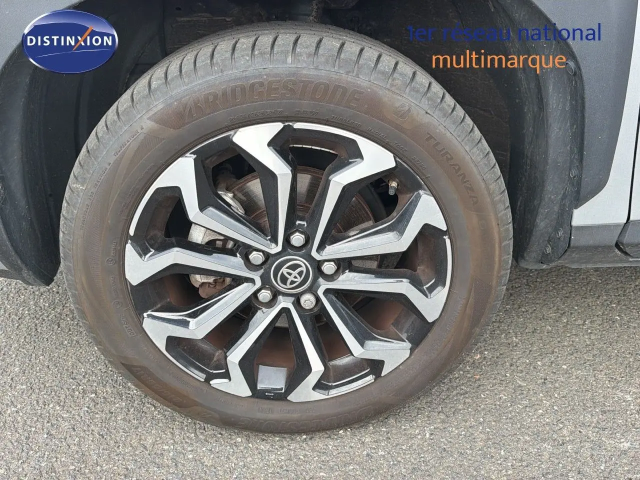 Gros plan sur la roue avant droite de la Toyota Yaris Cross gris minéral avec jante alliage noire et argentée.
