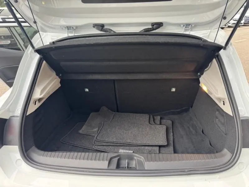 Coffre ouvert vu de l'arrière d'une Renault Clio 2023 blanc glacier avec tapis de sol gris à l'intérieur.