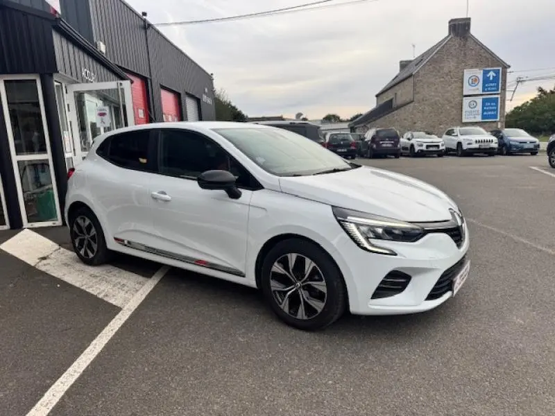 Renault Clio blanc glacier vue 3/4 avant droit, avec jantes noires et détails rouges sur les bas de caisse.