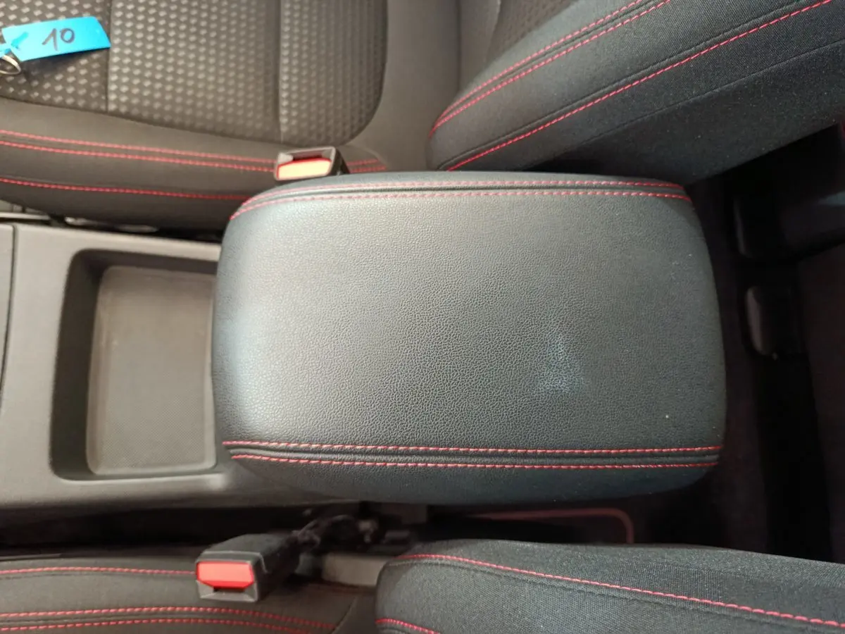 Vue rapprochée de l'accoudoir central noir avec surpiqûres rouges dans l'habitacle du Ford Kuga 2024.