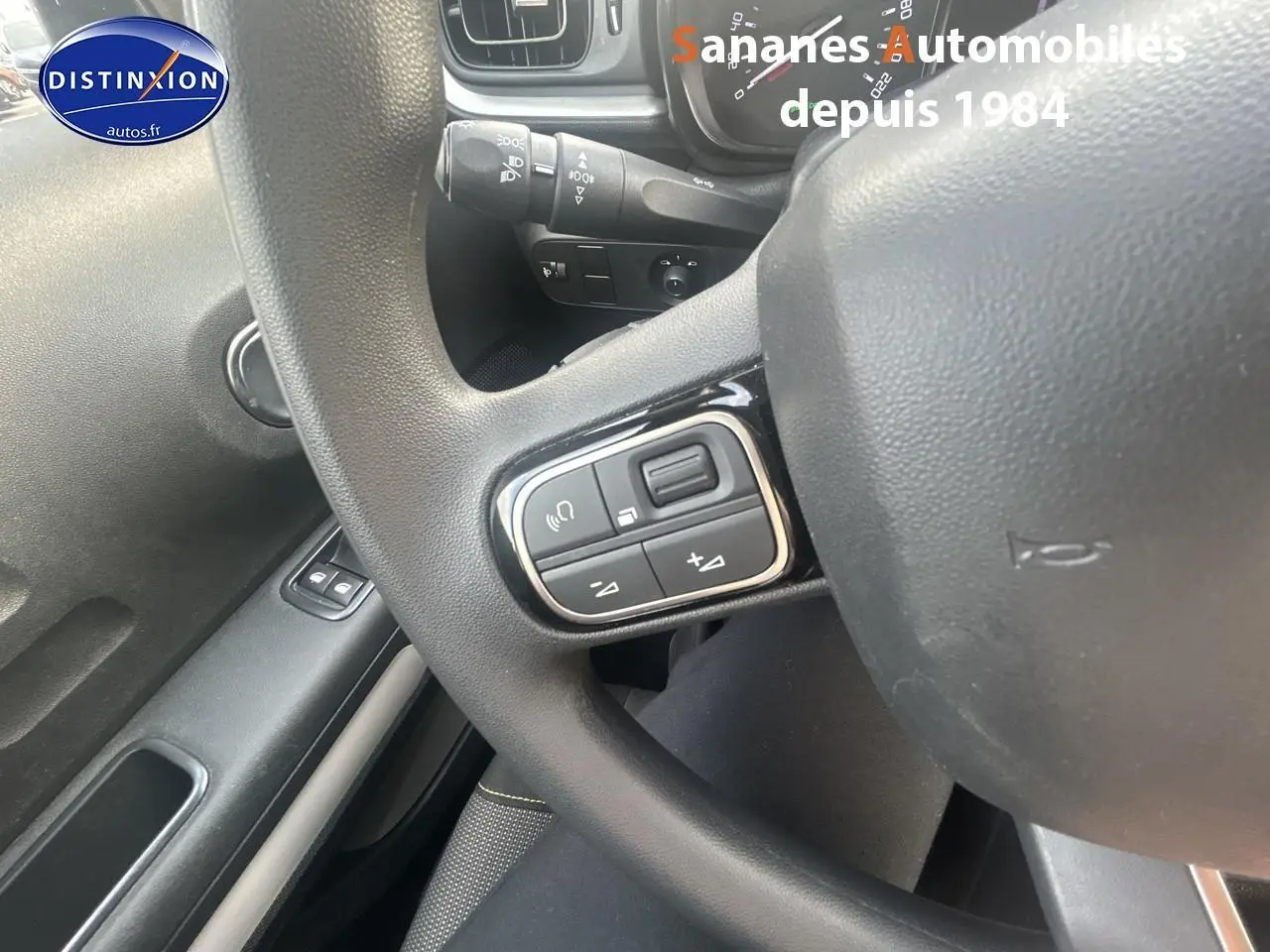 Gros plan sur le volant avec commandes audio au volant dans l'habitacle d'une Citroën C3 gris foncé 2023.