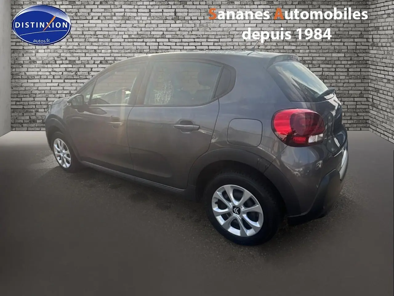 Citroën C3 gris foncé vue 3/4 arrière côté droit, avec jantes alliage et feux arrière arrondis.