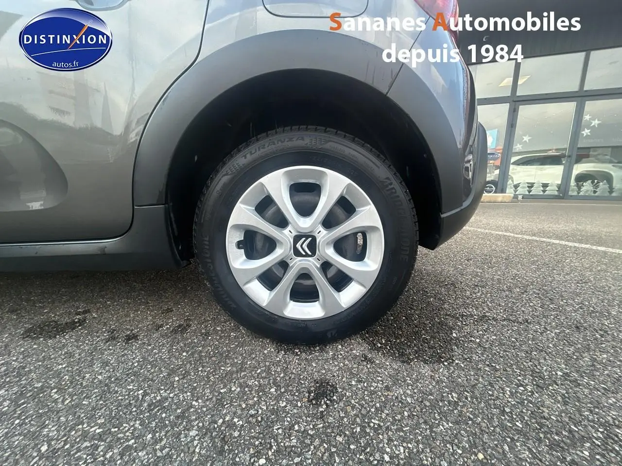 Gros plan sur la roue arrière droite d'une Citroën C3 gris foncé 2023 avec jante alliage et logo Citroën visible.