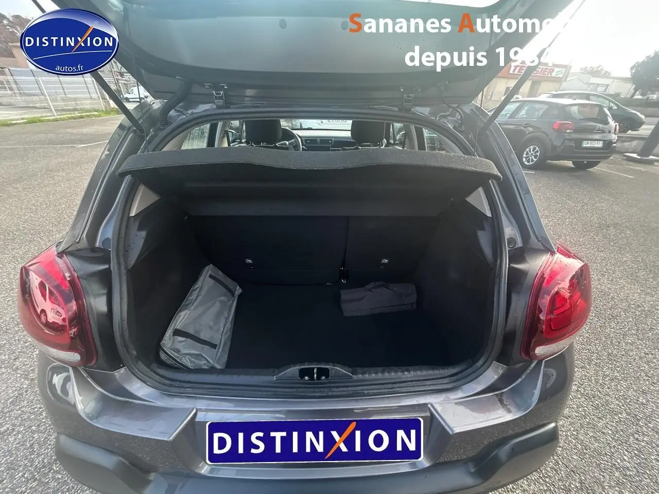 Coffre ouvert vu de l'arrière d'une Citroën C3 1.5 BlueHDi gris foncé 2023, avec objets à l'intérieur.