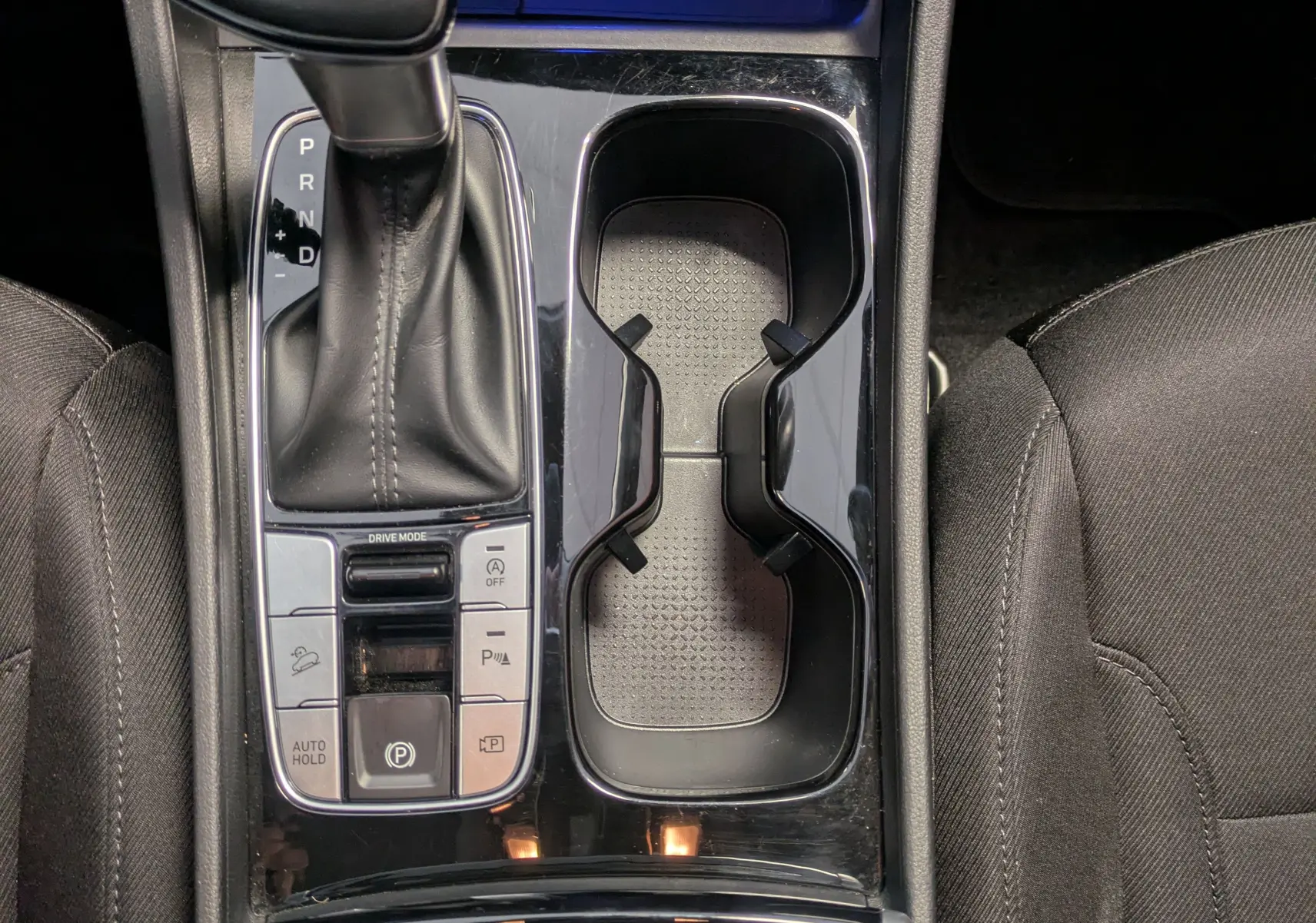 Vue rapprochée de la console centrale du Hyundai Tucson blanc 2021, avec levier de vitesse automatique et commandes sièges chauffants.