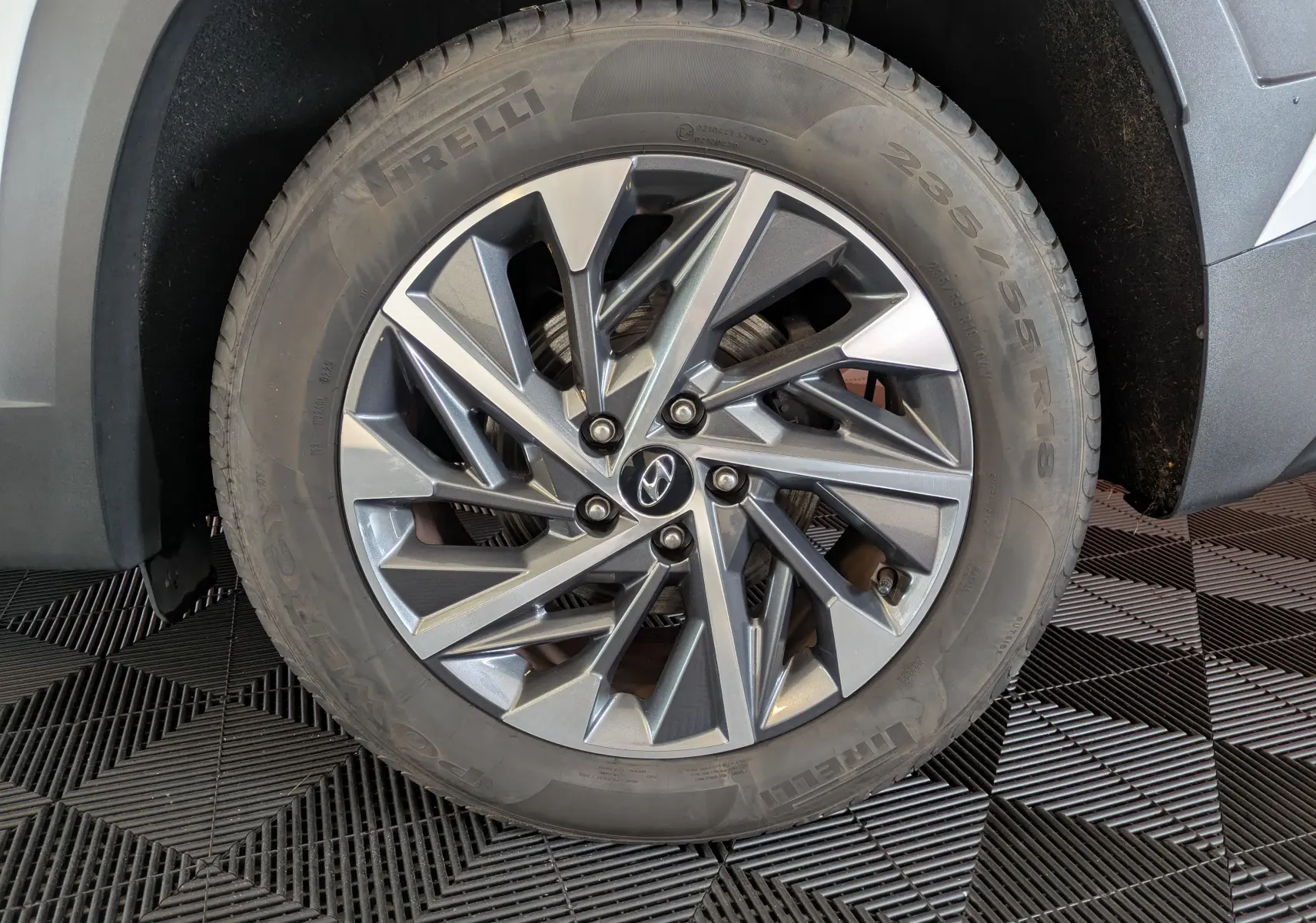 Gros plan sur la jante alliage grise et le pneu Pirelli du Hyundai Tucson blanc, côté avant droit.