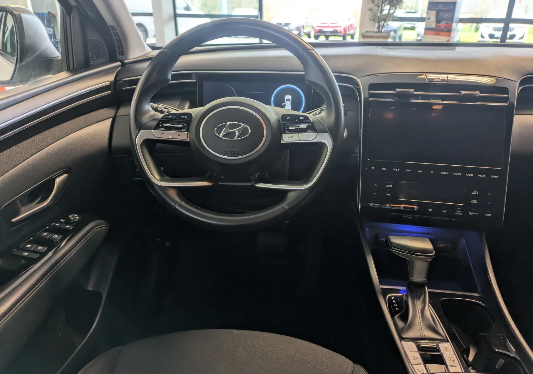 Vue intérieure du tableau de bord et volant du Hyundai Tucson 2021, avec écran tactile et levier de vitesse automatique.