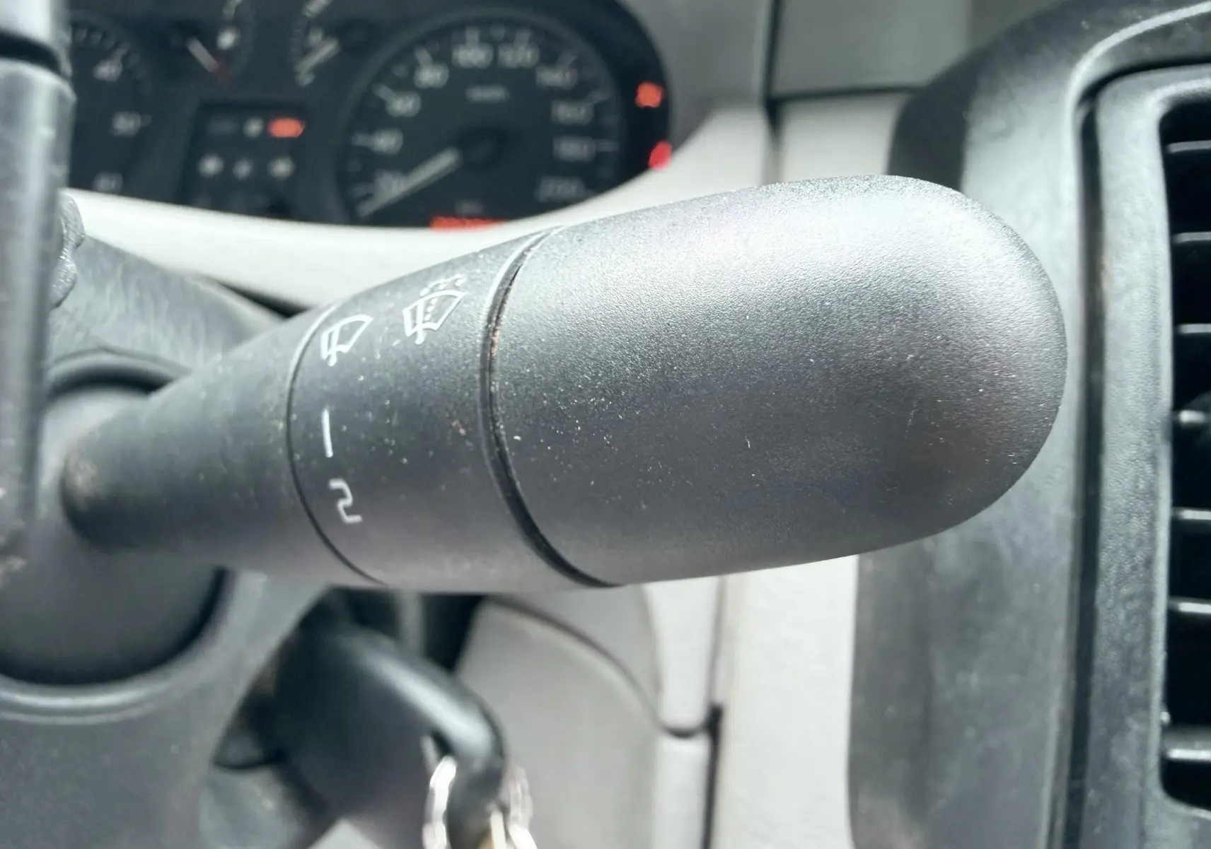 Gros plan sur la manette d’essuie-glace du tableau de bord intérieur d’un Nissan Primastar blanc de 2005.