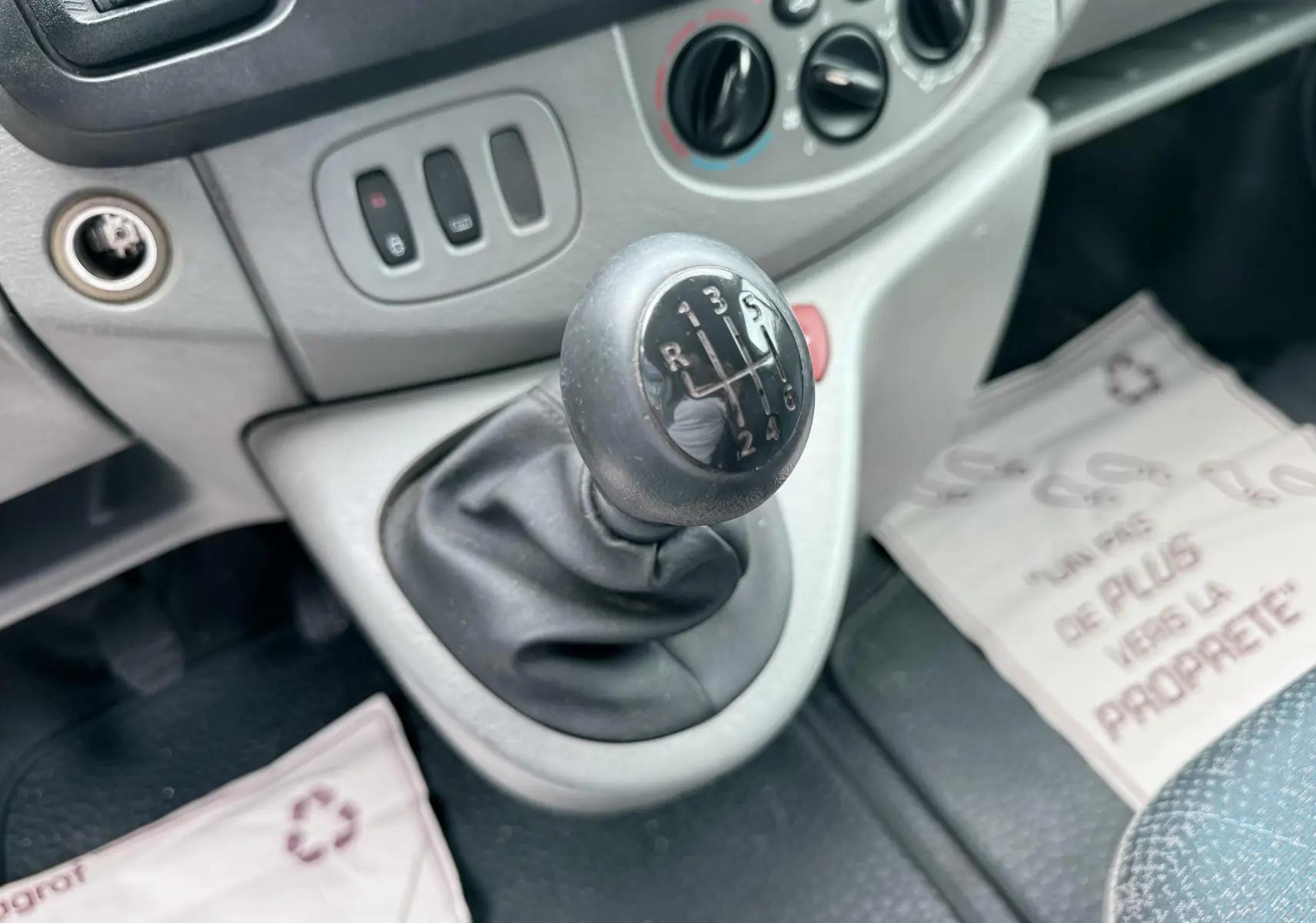 Gros plan sur le levier de vitesses manuel noir dans l’habitacle gris clair du Nissan Primastar blanc.