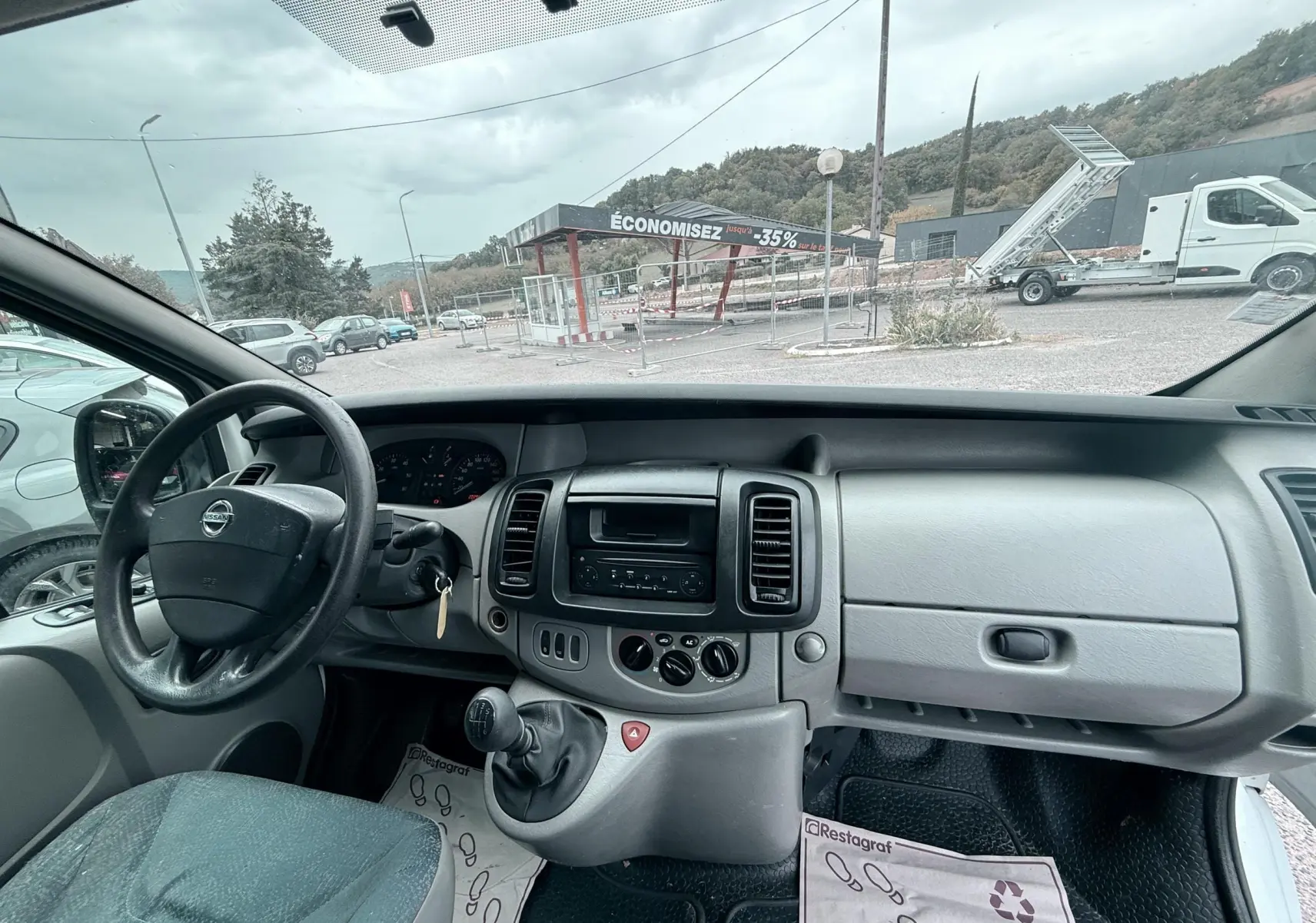Vue intérieure du tableau de bord gris bleu et volant cuir du Nissan Primastar 2005 côté conducteur.