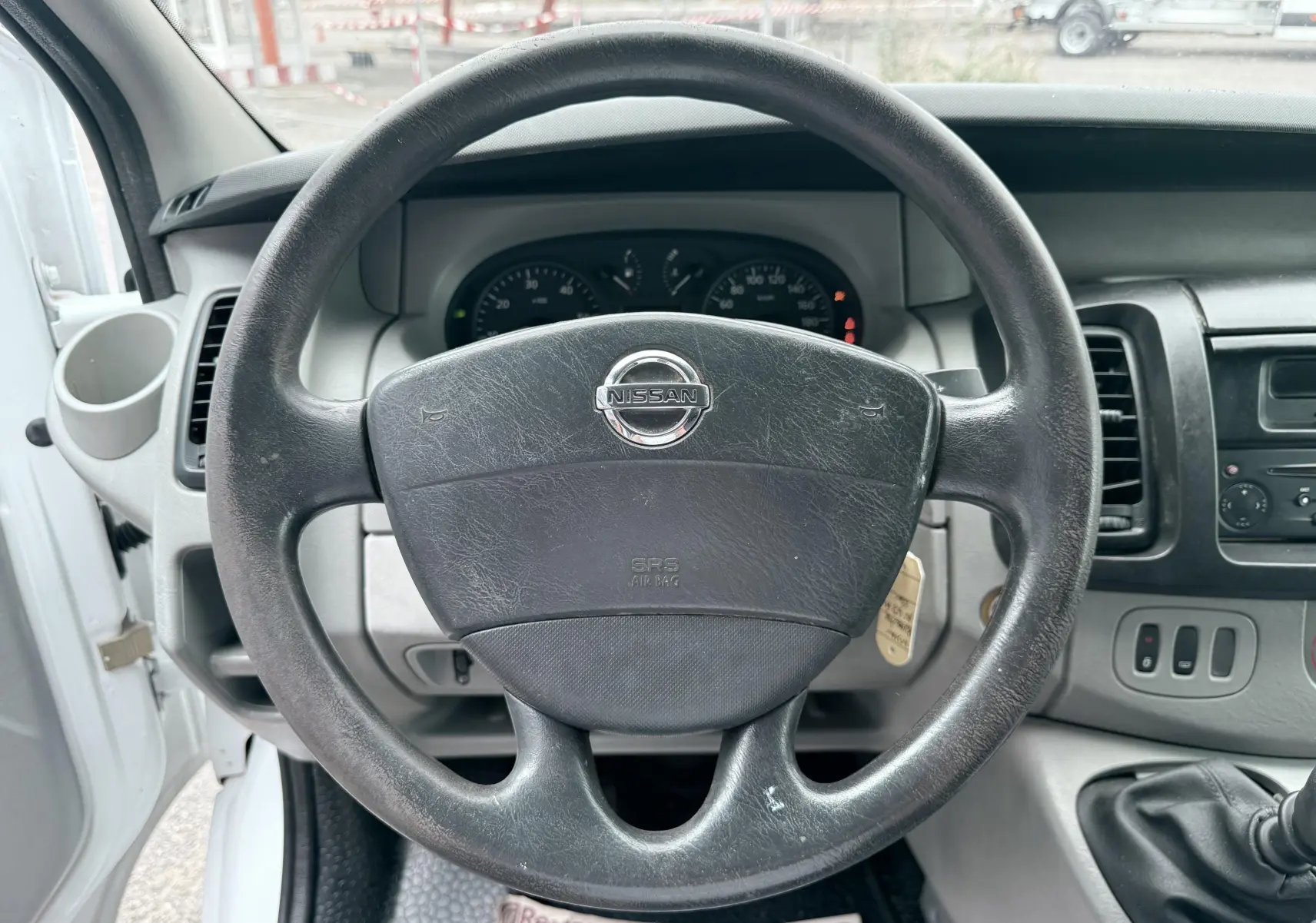 Vue rapprochée du volant noir Nissan Primastar 2005 avec tableau de bord et levier de vitesses manuel visibles.