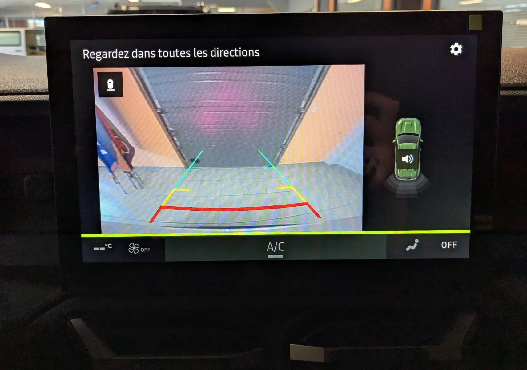 Écran intérieur montrant la caméra de recul du Dacia Duster blanc glacier avec guidage de trajectoire coloré.