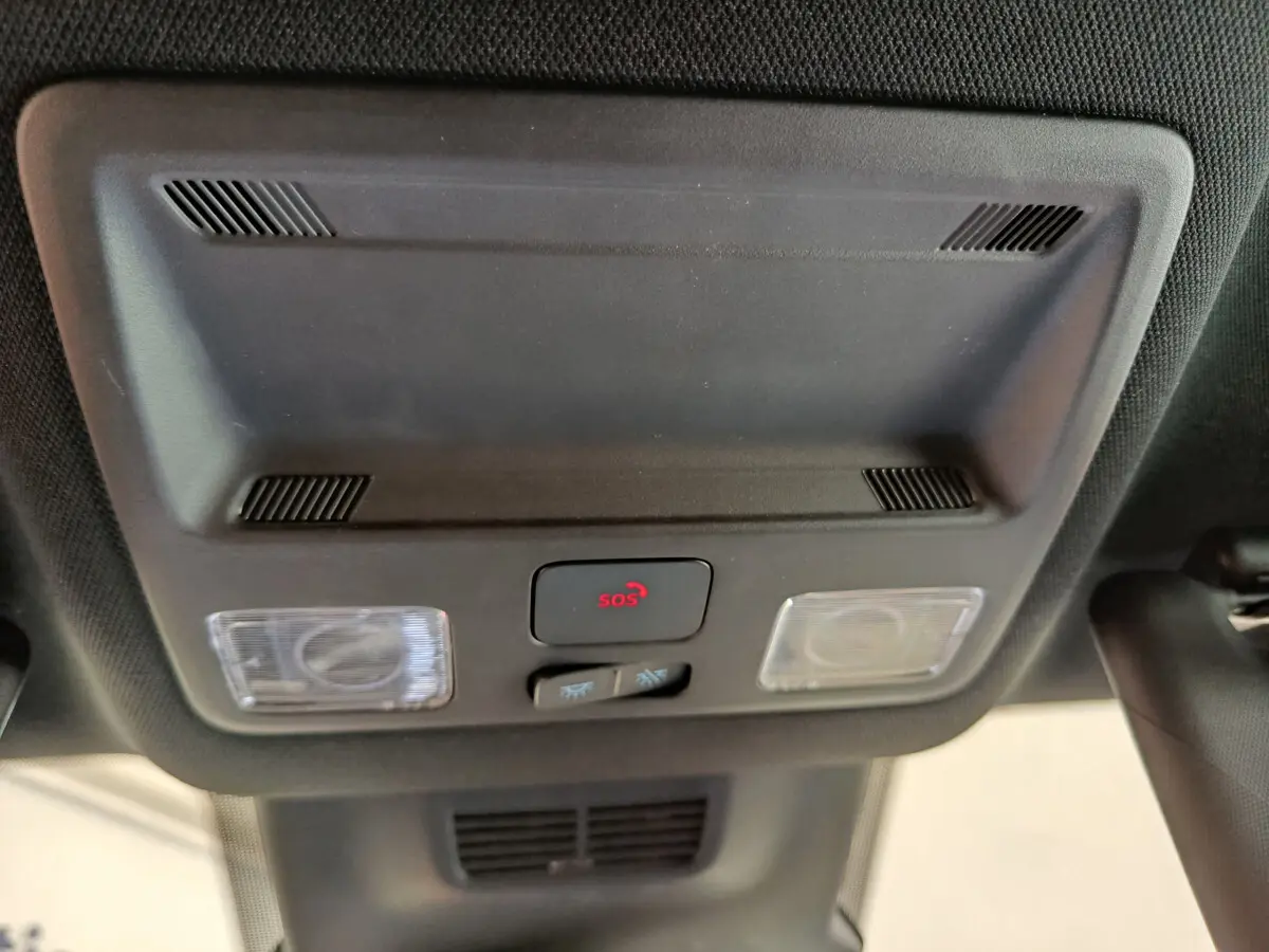 Vue en gros plan du plafonnier intérieur noir avec bouton SOS rouge et éclairages sur Ford Puma bleu 2025.