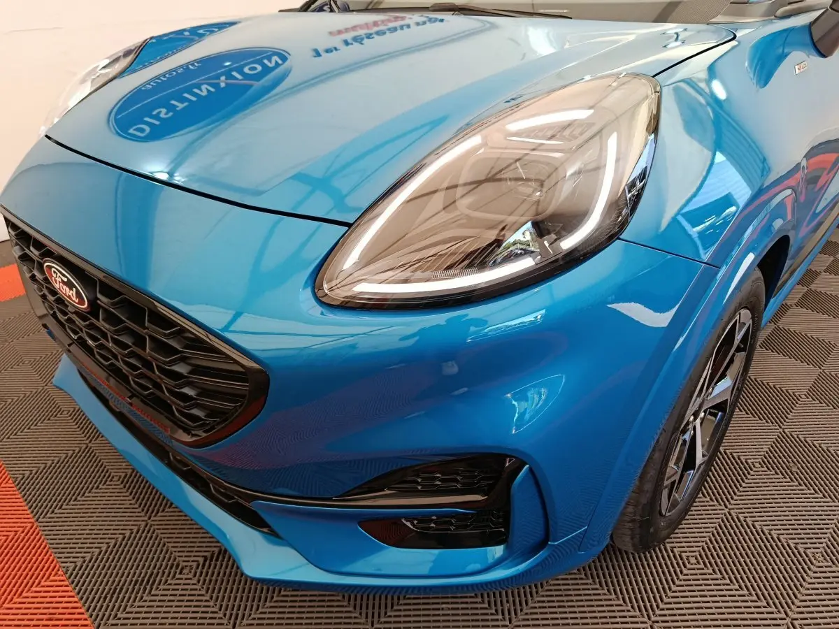 Vue 3/4 avant droit d'une Ford Puma bleu vif avec phares LED et calandre noire en nid d'abeille.