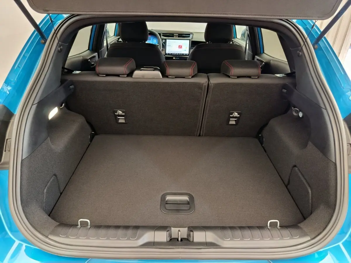 Vue arrière du coffre ouvert d’un Ford Puma bleu 2025, montrant la banquette arrière et l’écran tactile du tableau de bord.