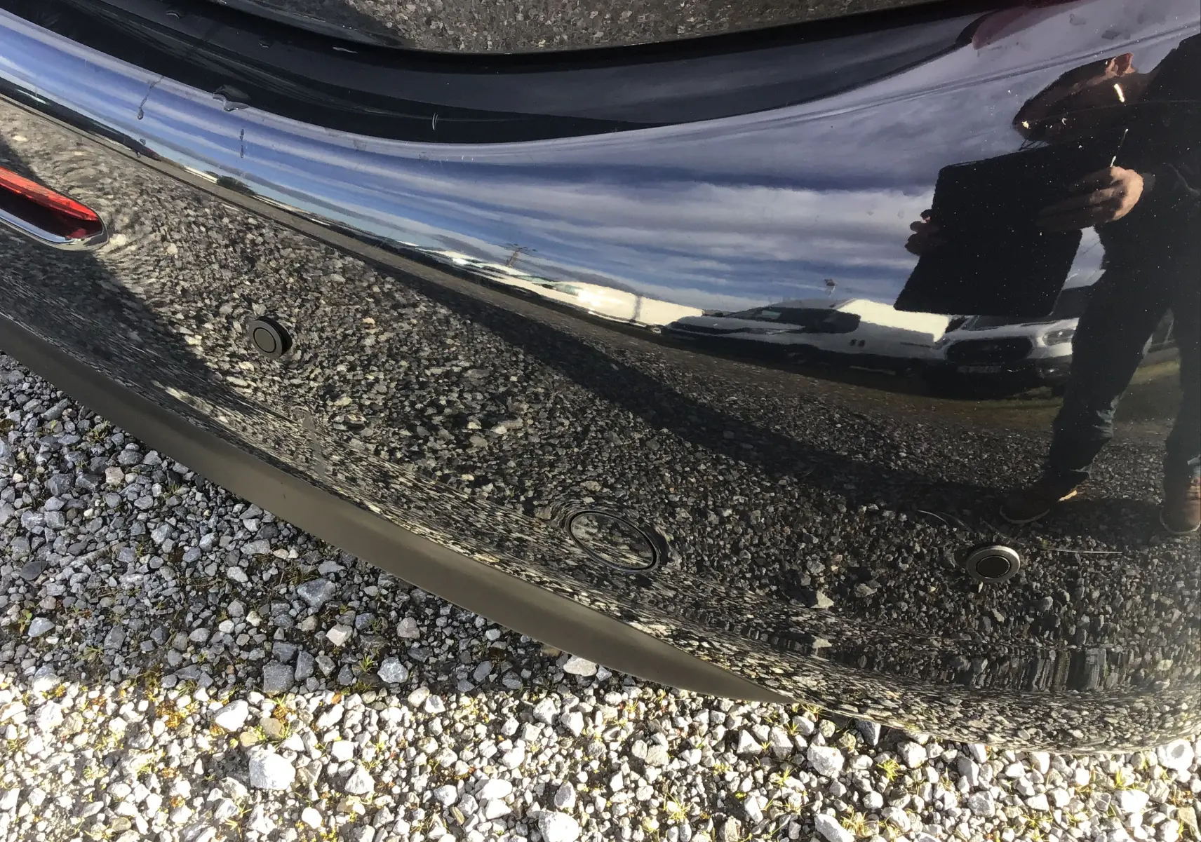 Gros plan sur le pare-chocs arrière noir brillant du Peugeot 208 2018 avec capteurs de recul visibles.