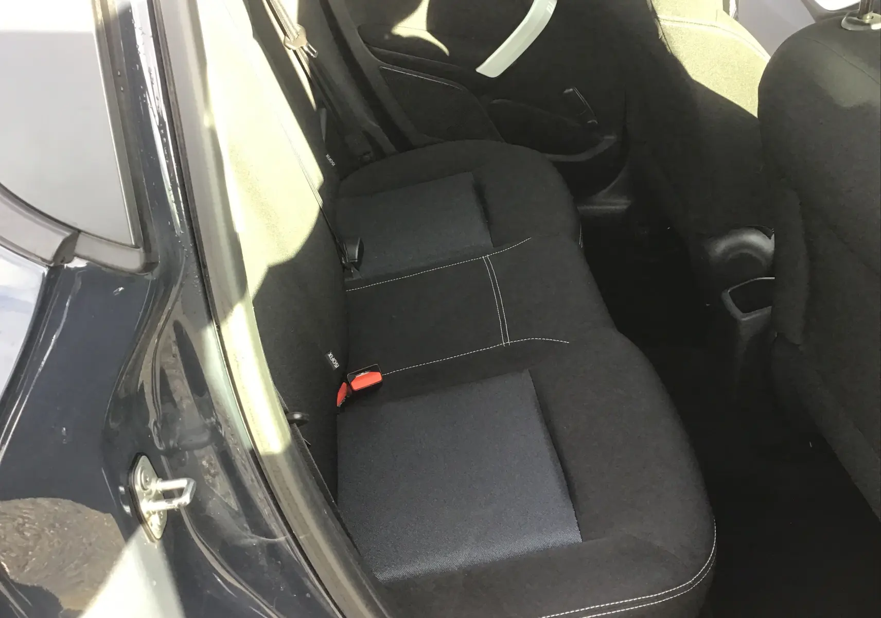 Vue intérieure côté gauche des sièges arrière noirs avec surpiqûres blanches d'une Peugeot 208 2018 essence.