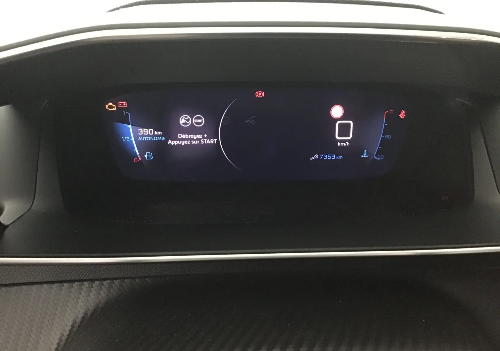 Tableau de bord numérique de la Peugeot 208 GT 2023 affichant autonomie, vitesse et température moteur en vue frontale.