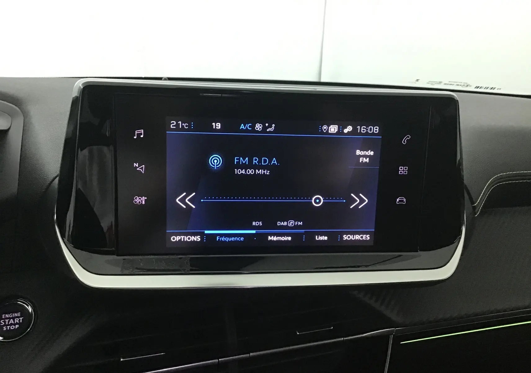 Écran tactile central allumé dans l'habitacle noir du Peugeot 208 GT 1.2 PureTech 2023, affichant une radio FM.