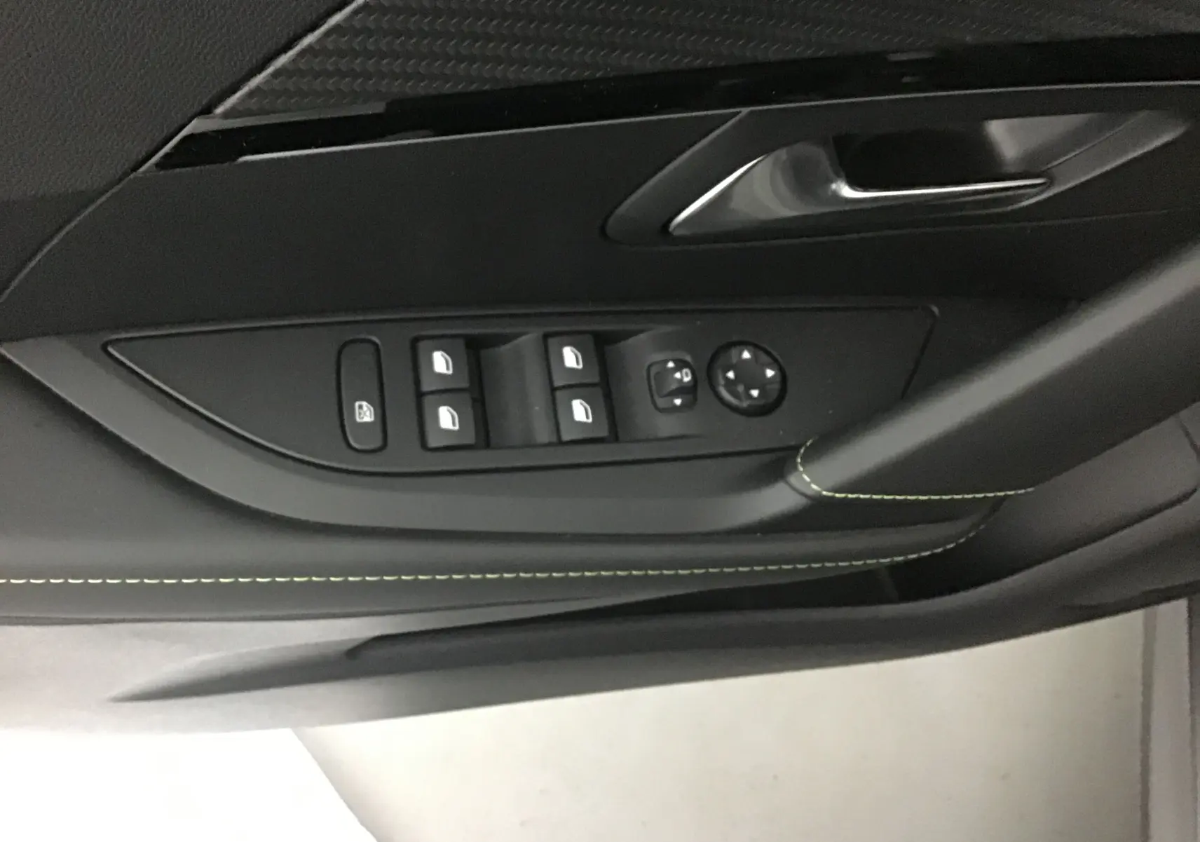 Gros plan sur la commande des vitres et rétroviseurs côté conducteur d'une Peugeot 208 gris platinium/noir 2023.