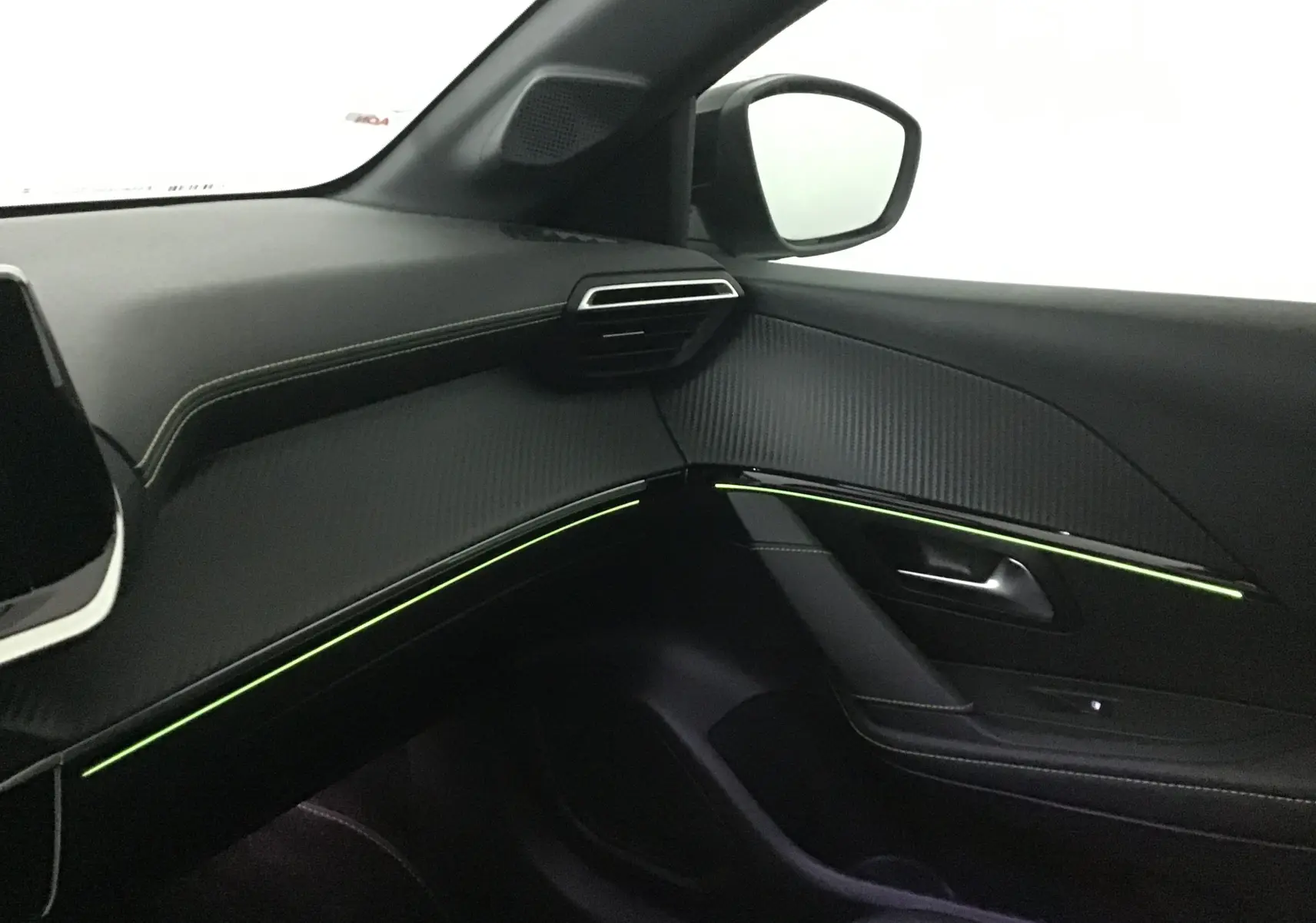 Intérieur côté passager du Peugeot 208 1.2 PureTech 100 GT 2023, avec éclairage d'ambiance vert et finitions noires.