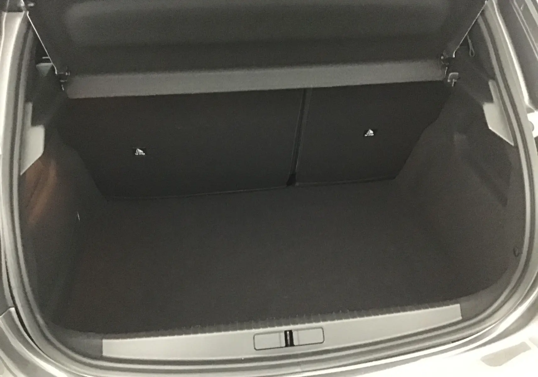 Coffre ouvert de la Peugeot 208 gris platinium/noir, vue de dessus montrant l'espace de chargement vide.
