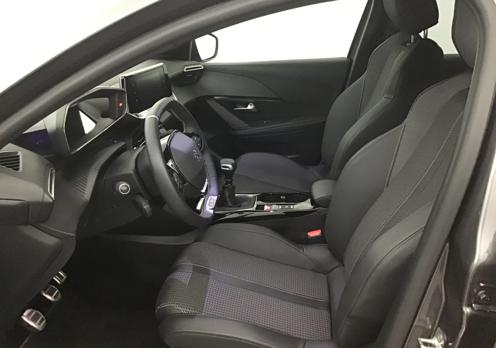 Intérieur avant gauche du Peugeot 208 1.2 PureTech 100 GT S&S 2023 avec sièges cuir et volant multifonction.