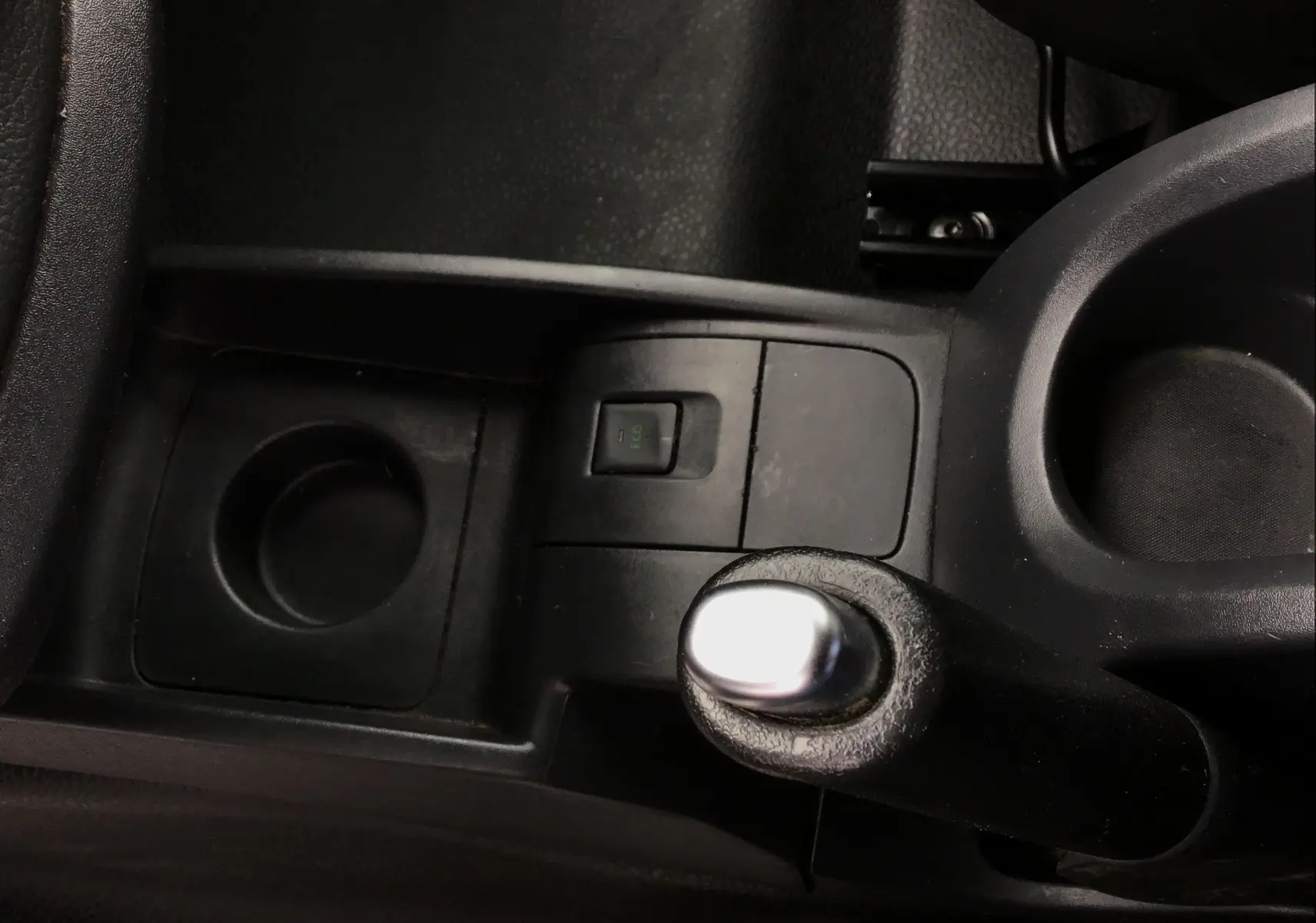 Le levier de frein à main noir vu de dessus dans l'habitacle du Renault Kangoo blanc de 2019.