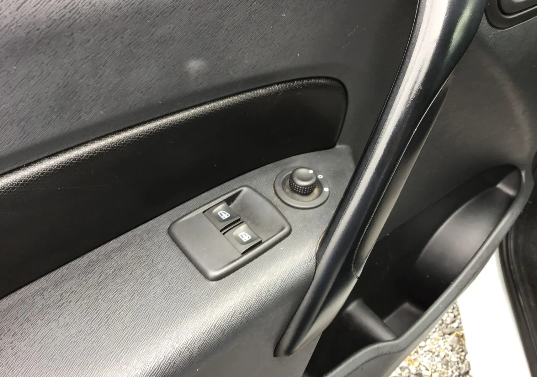 Détail de la porte avant gauche du Renault Kangoo blanc 2019, avec commandes électriques des vitres et réglage des rétroviseurs.