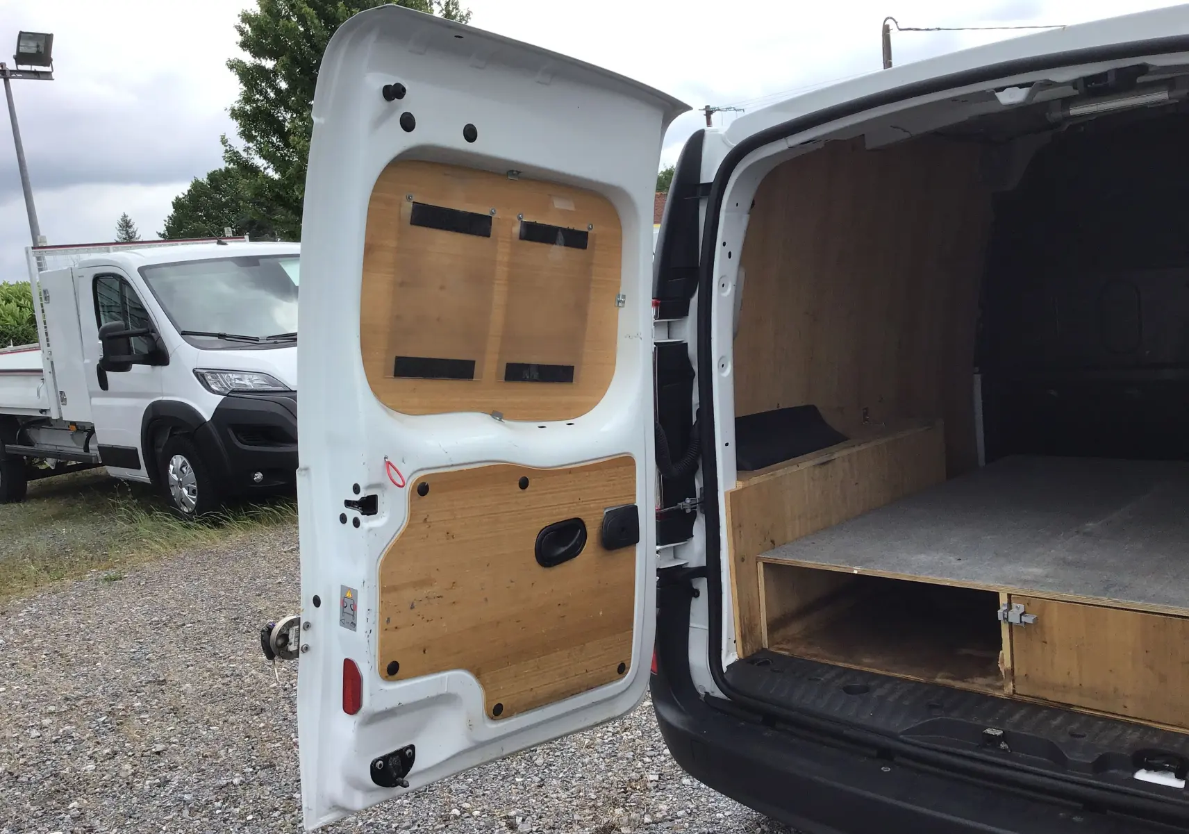 Vue arrière ouverte du Renault Kangoo blanc 2019 avec aménagement bois intérieur et cloison séparatrice visible.