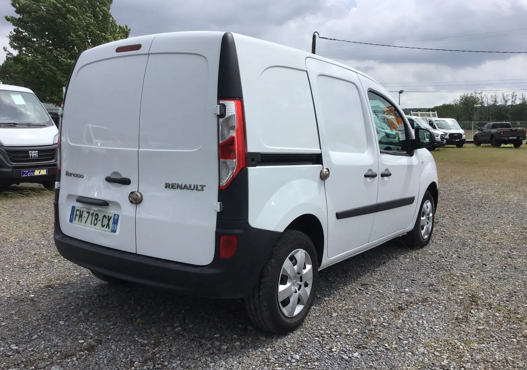 Renault Kangoo blanc vu en 3/4 arrière droit, fourgonnette utilitaire avec portes arrière battantes et poignées noires.