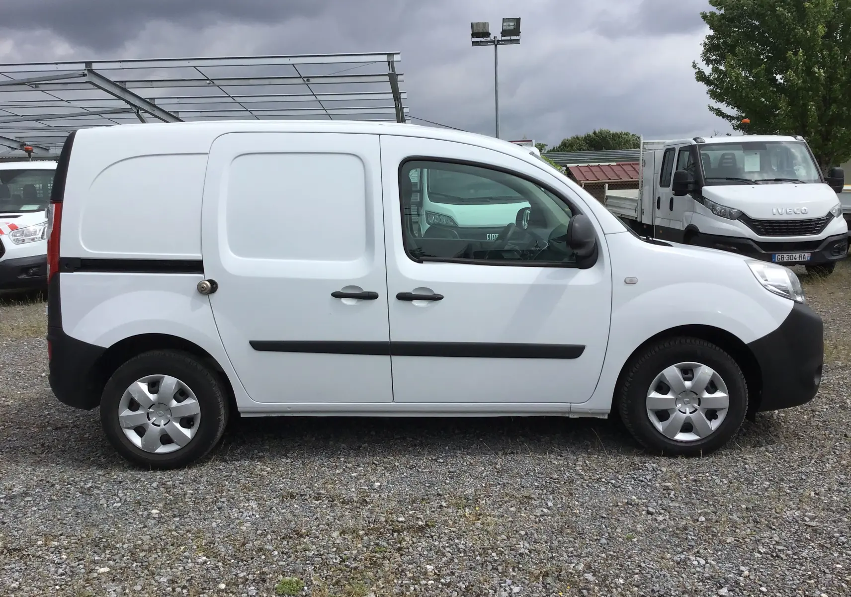 Profil côté droit du Renault Kangoo blanc 2019, version utilitaire avec portes latérales et protections noires.