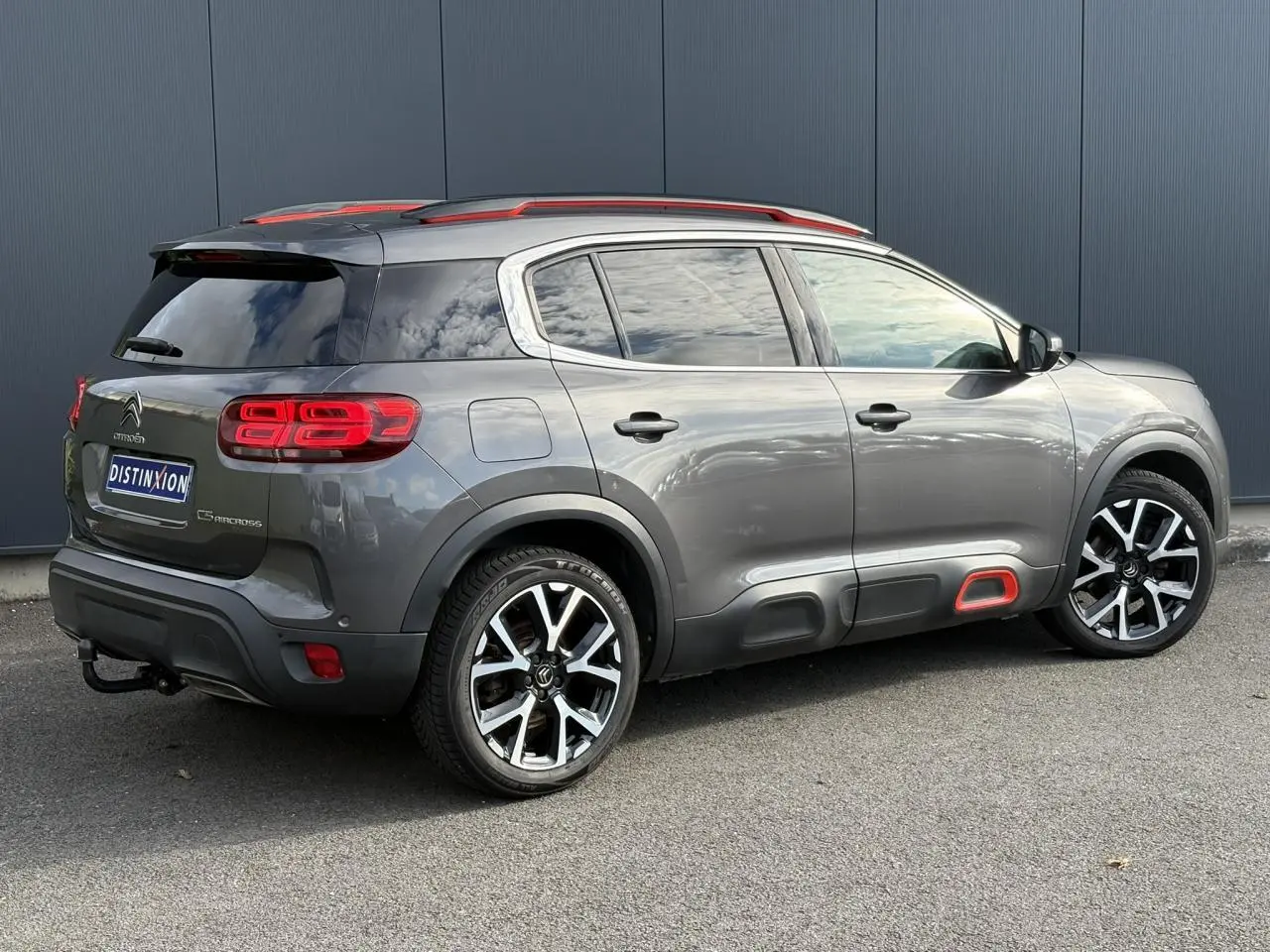 Vue 3/4 arrière droit d'un Citroën C5 Aircross gris Platinium avec jantes alliage 19" et inserts rouges distinctifs.