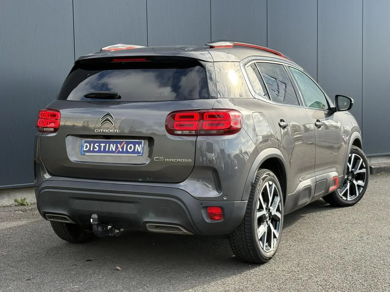 Vue 3/4 arrière droite d'un Citroën C5 Aircross gris Platinium avec jantes alliage et attelage visible.