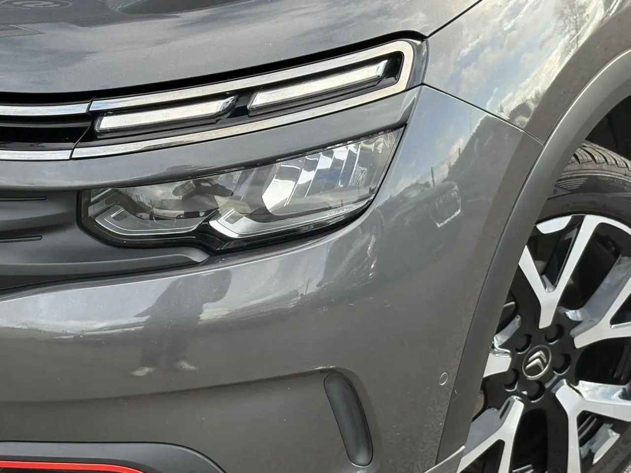 Gros plan sur le phare avant gauche et la jante alliage 19 pouces du Citroën C5 Aircross Gris Platinium.