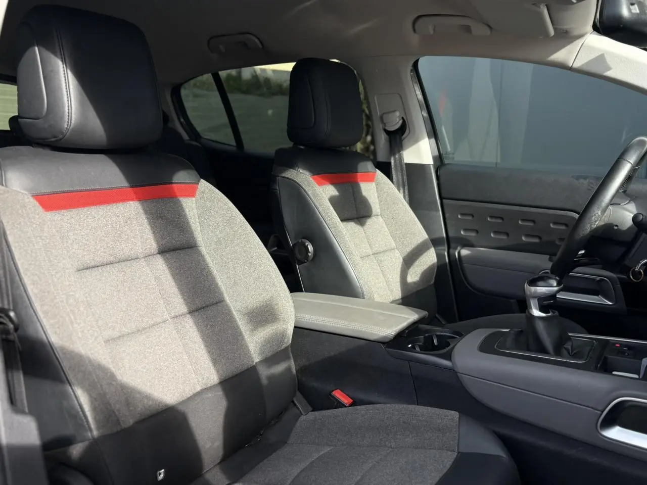 Vue intérieure avant du Citroën C5 Aircross 2020 avec sièges gris clair et inserts rouges sur appuie-têtes et dossier.