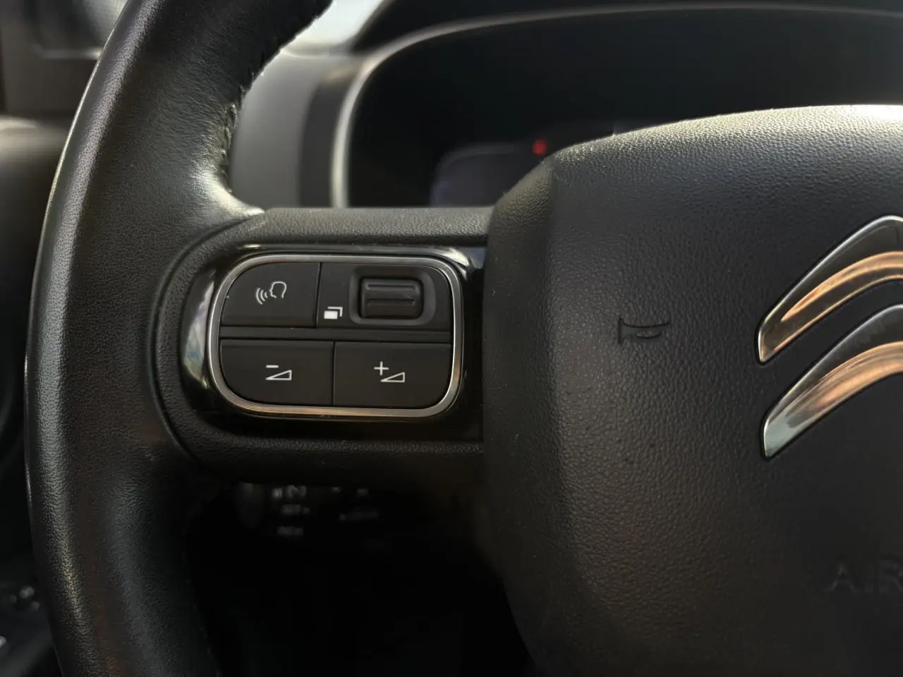 Gros plan sur les commandes gauche du volant en cuir noir du Citroën C5 Aircross 1.5 BlueHDi 130 Feel.
