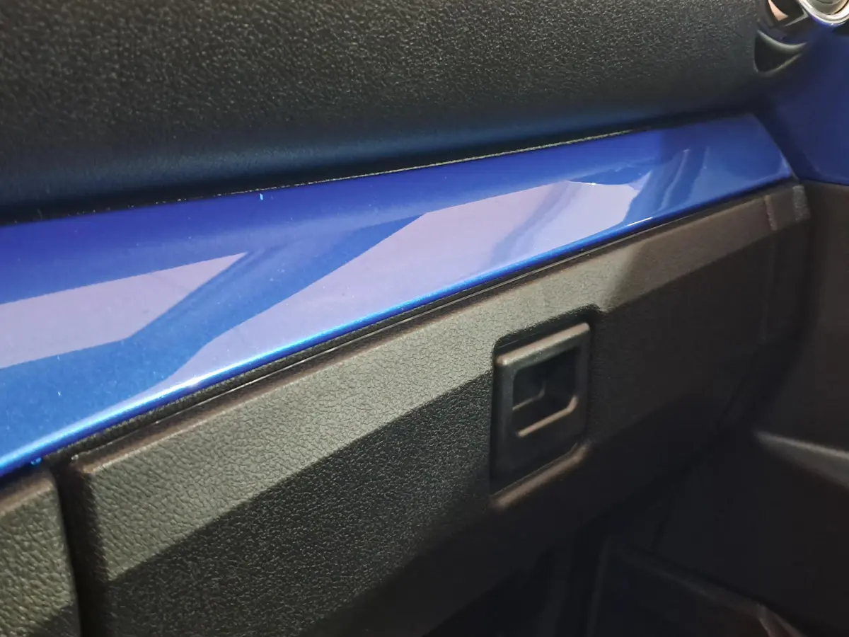 Détail intérieur montrant la planche de bord avec bandeau bleu brillant sur AIXAM AMBITION 2026 côté passager.