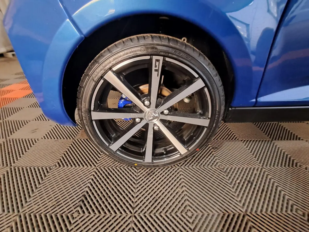 Gros plan sur la roue avant gauche bleu métallisé d'une Aixam Ambition 2026 avec jante noire et détails gris.