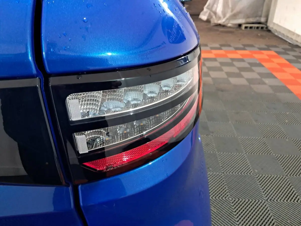 Gros plan sur le feu arrière droit bleu métallisé de l'AIXAM AMBITION 0.5 CITY GTO 2026 dans un garage.