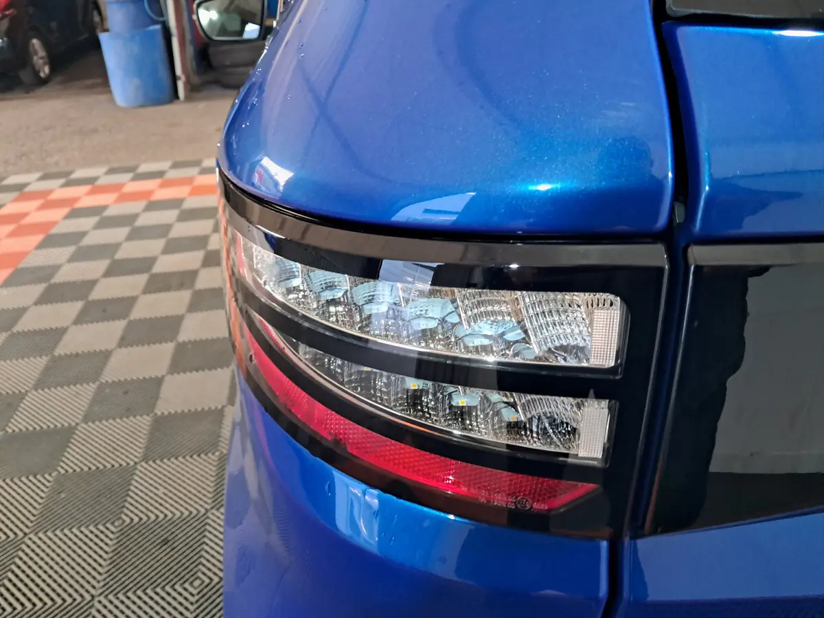 Gros plan sur le feu arrière droit bleu métallisé de l'AIXAM AMBITION 0.5 CITY GTO 2026 dans un garage.