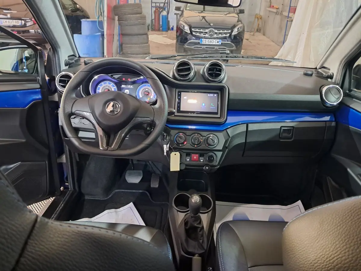 Vue intérieure avant de l'AIXAM Ambition 2026 bleu, tableau de bord avec écran tactile et volant multifonction.