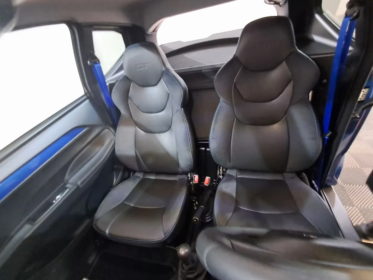 Vue intérieure des sièges avant noirs de l'AIXAM AMBITION 0.5 CITY GTO avec ceinture bleue côté gauche.