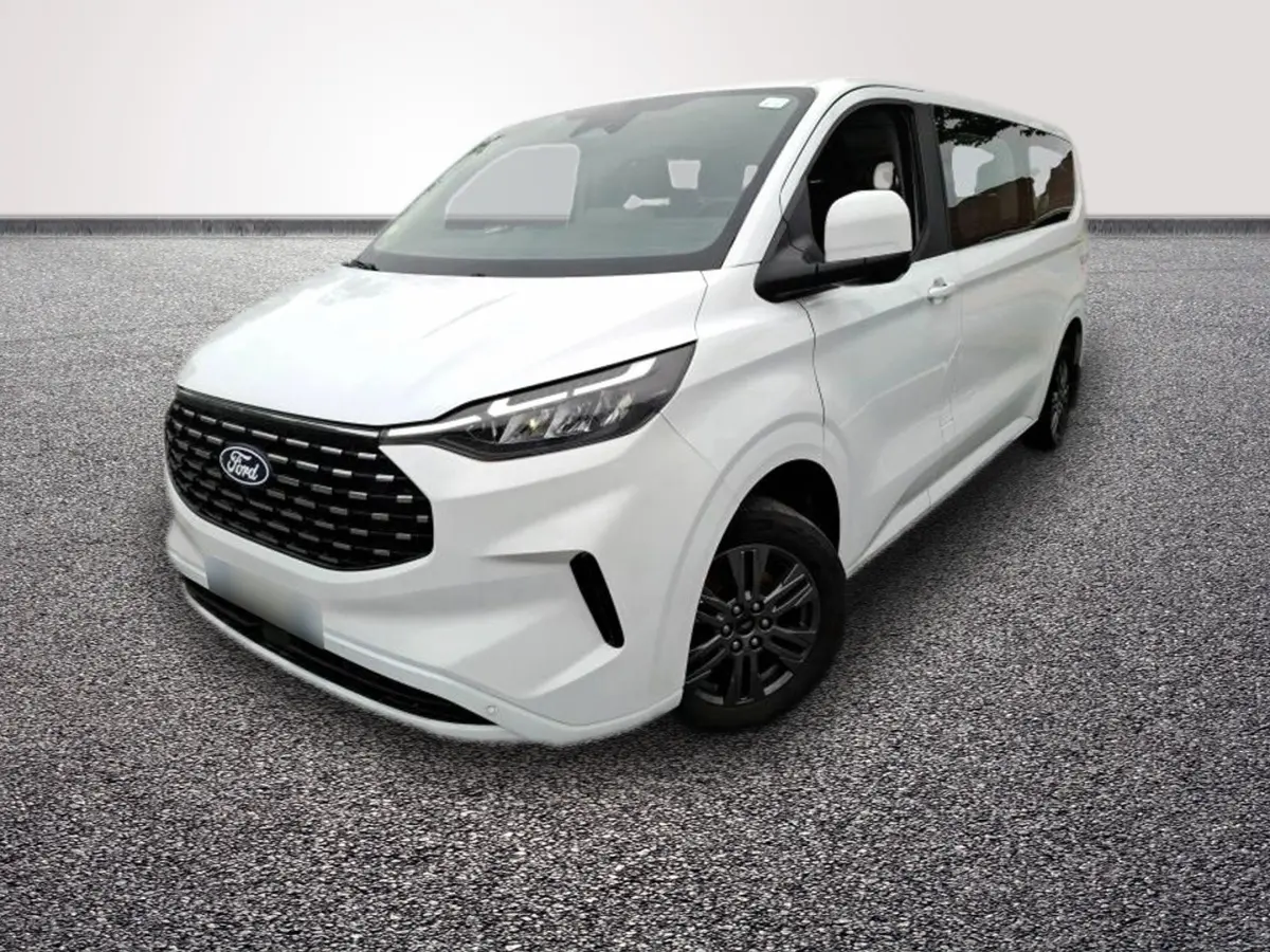 Ford Tourneo Custom blanc en 3/4 avant droit, avec calandre noire et jantes foncées visibles sur sol gris.