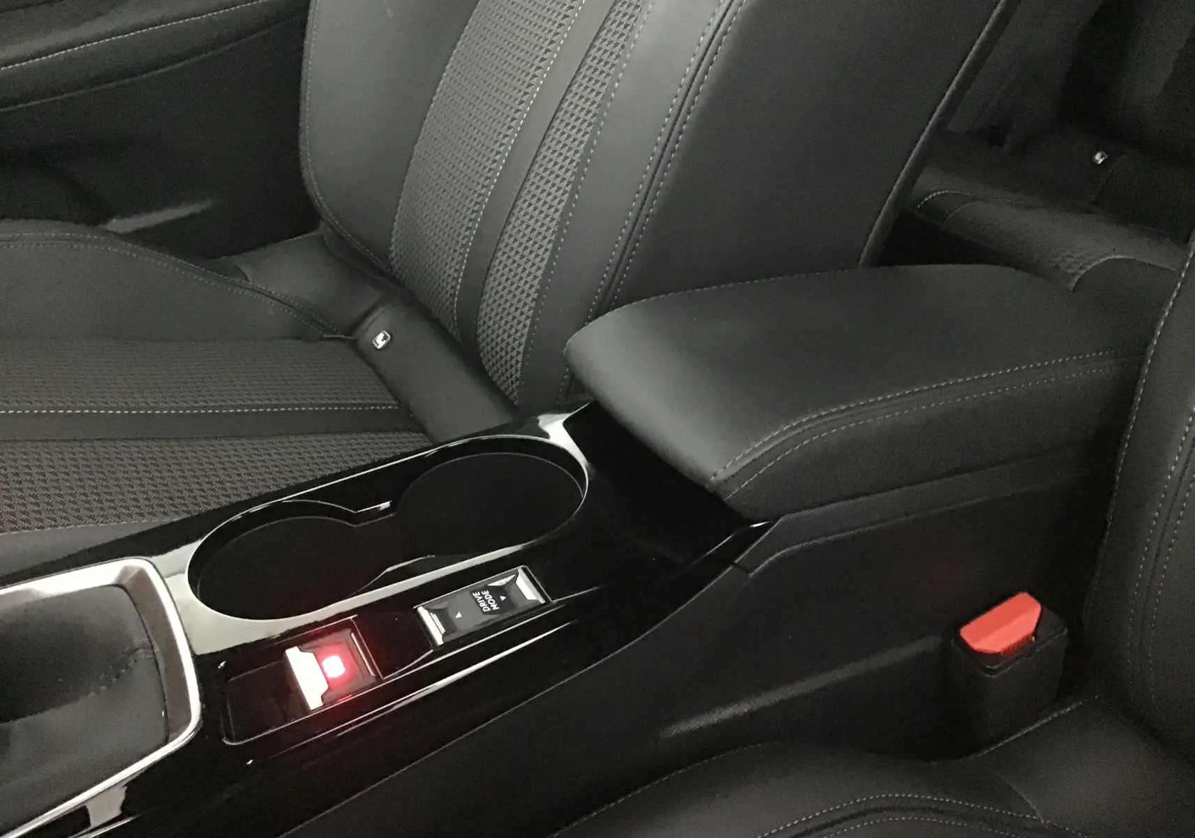 Gros plan sur la console centrale noire et les sièges en cuir noir de la Peugeot 208 1.2 PureTech 100 GT S&S 2023.