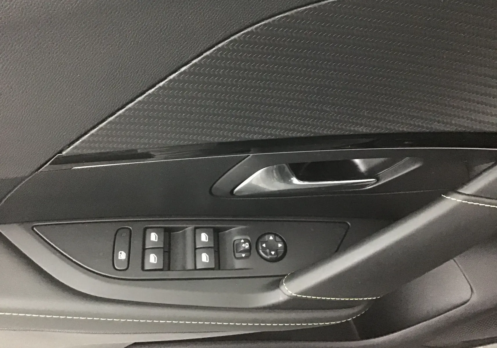 Détail de la porte côté conducteur de la Peugeot 208 1.2 PureTech 100 GT 2023 en gris platinium avec commandes des vitres et rétroviseurs.