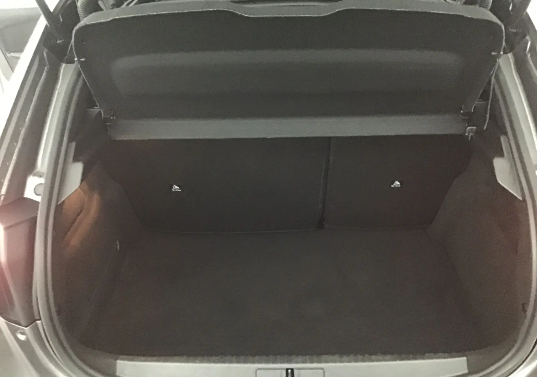Coffre ouvert vu de dessus du Peugeot 208 gris platinium/noir, montrant un espace de chargement vide et propre.