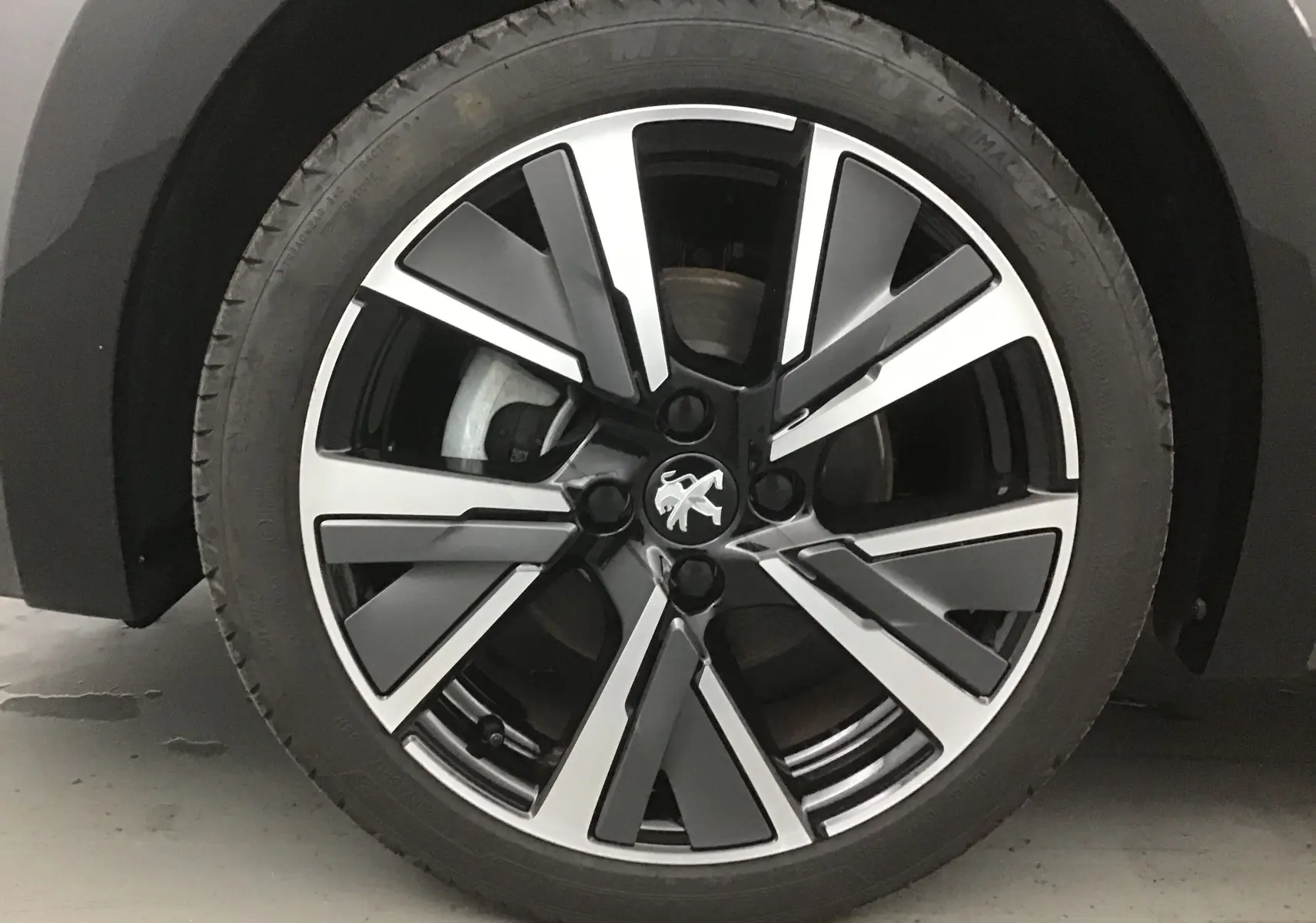 Gros plan sur la roue avant gauche de la Peugeot 208 1.2 PureTech 100 GT S&S gris platinium avec jante alliage noire et argent.
