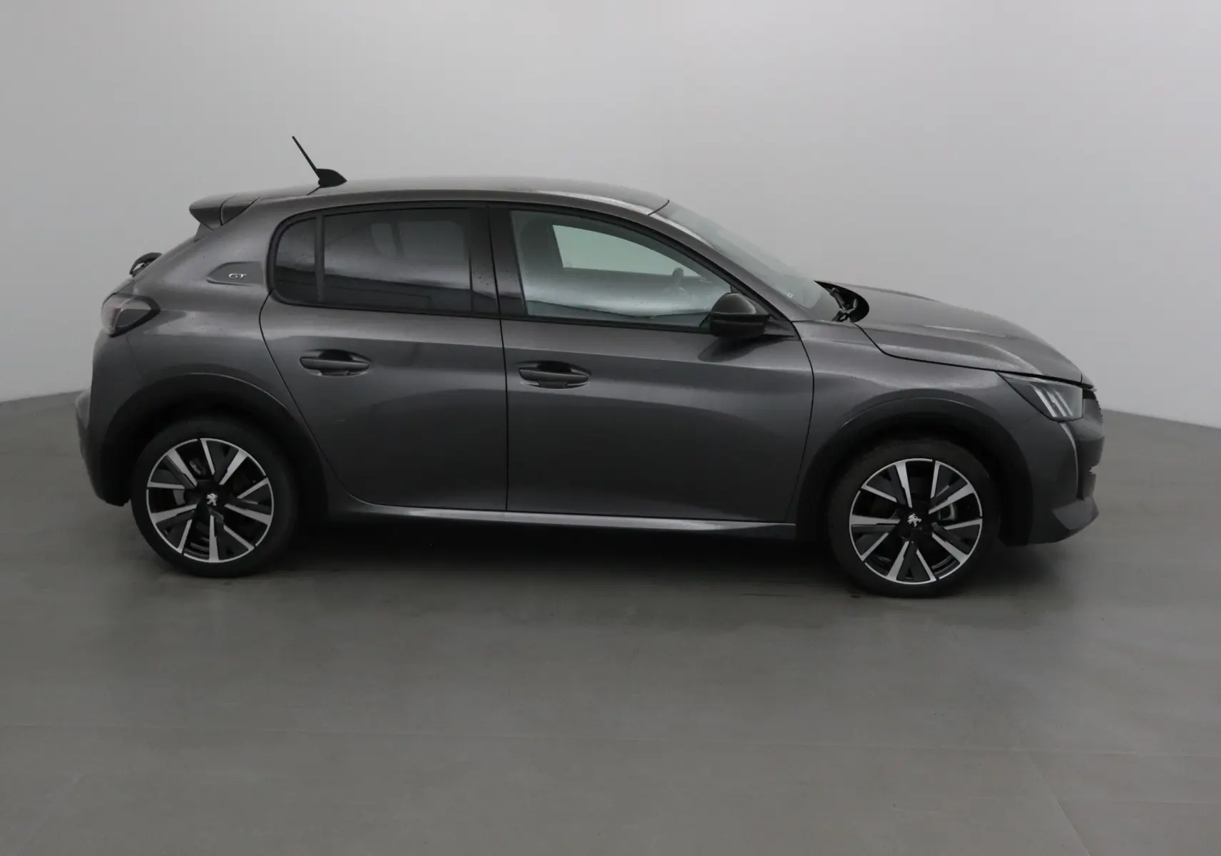 Profil côté gauche de la Peugeot 208 1.2 PureTech 100 GT gris platinium avec jantes alliage noires et détails noirs.